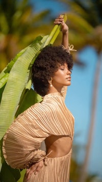 a woman in a golden dress posing with a banana leaf