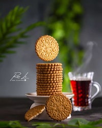 a stack of cookies on a plate next to a cup of tea